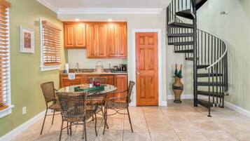 A kitchen with wooden cabinets, a dining table with chairs, and a spiral staircase.