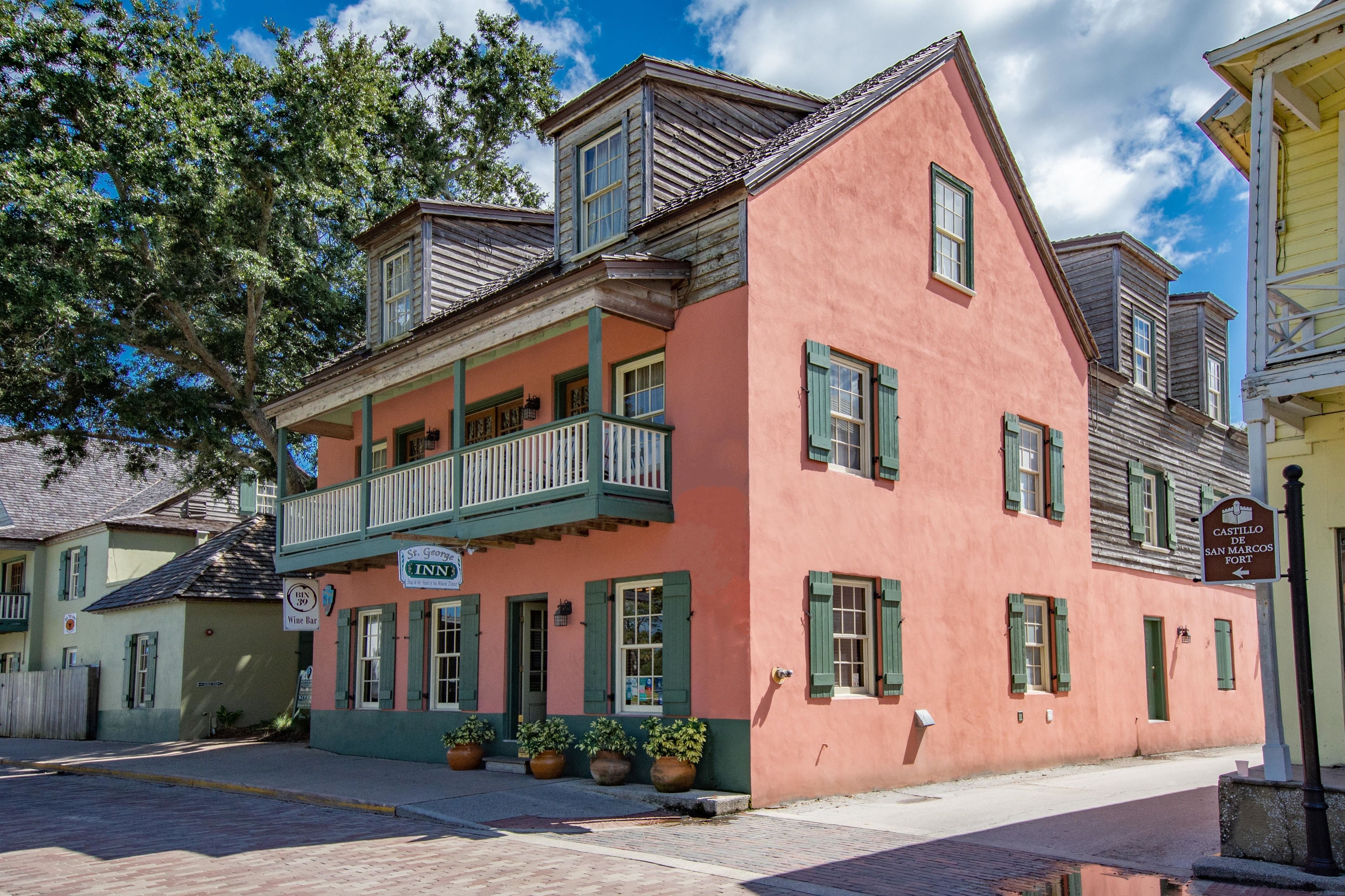 A pink building with a balcony and a sign for 'St. George Inn' and 'Wine Bar'.