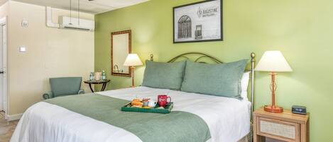 A hotel room with a bed, two bedside lamps, a ceiling fan, and a framed picture on the wall.