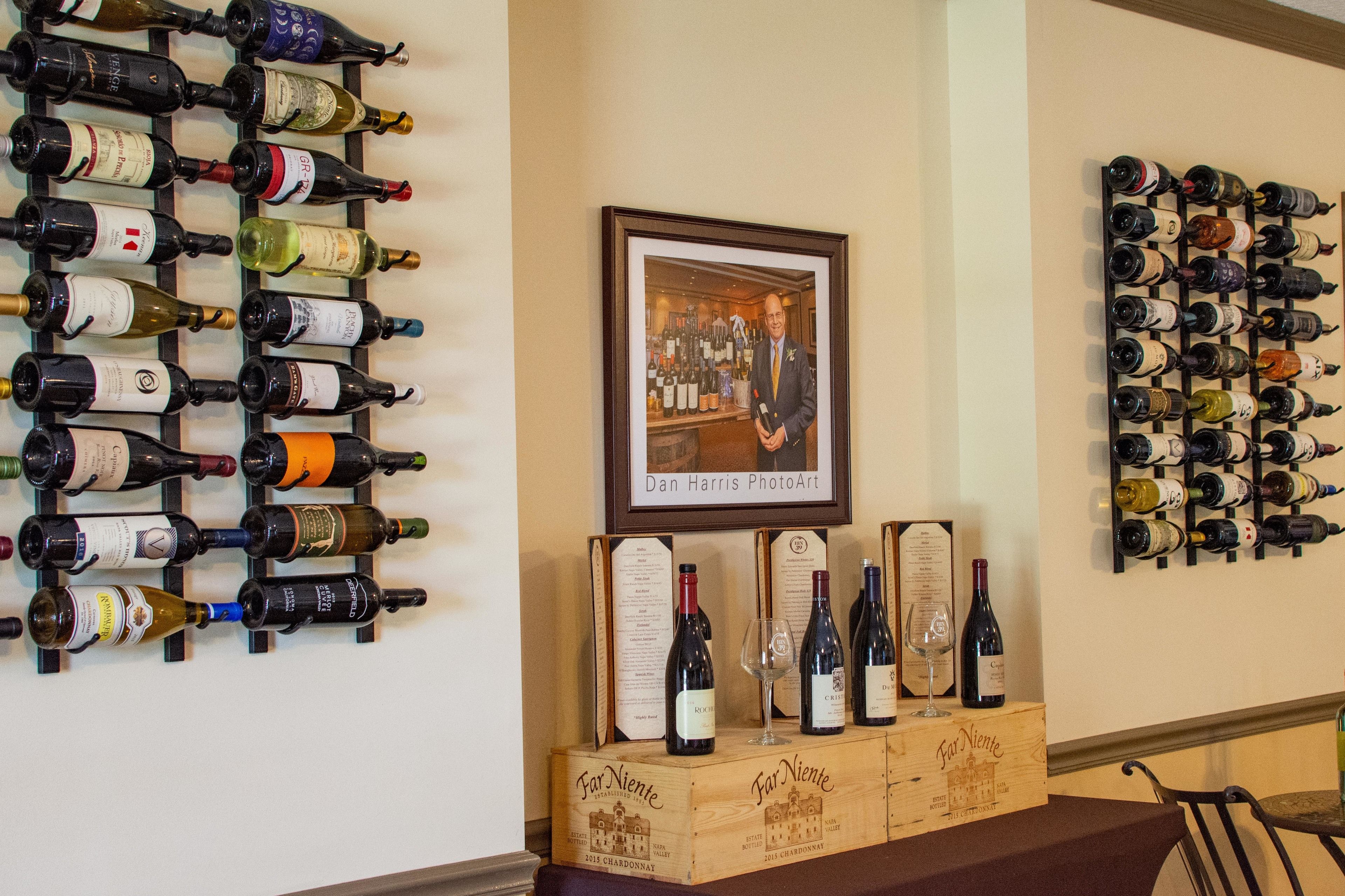 A wine rack with various bottles, a framed photo, and a wooden box with wine labels.