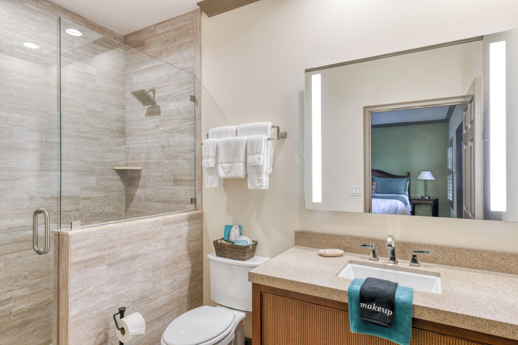 A modern bathroom with a glass shower enclosure, a toilet, a sink with a towel rack, and a large mirror.