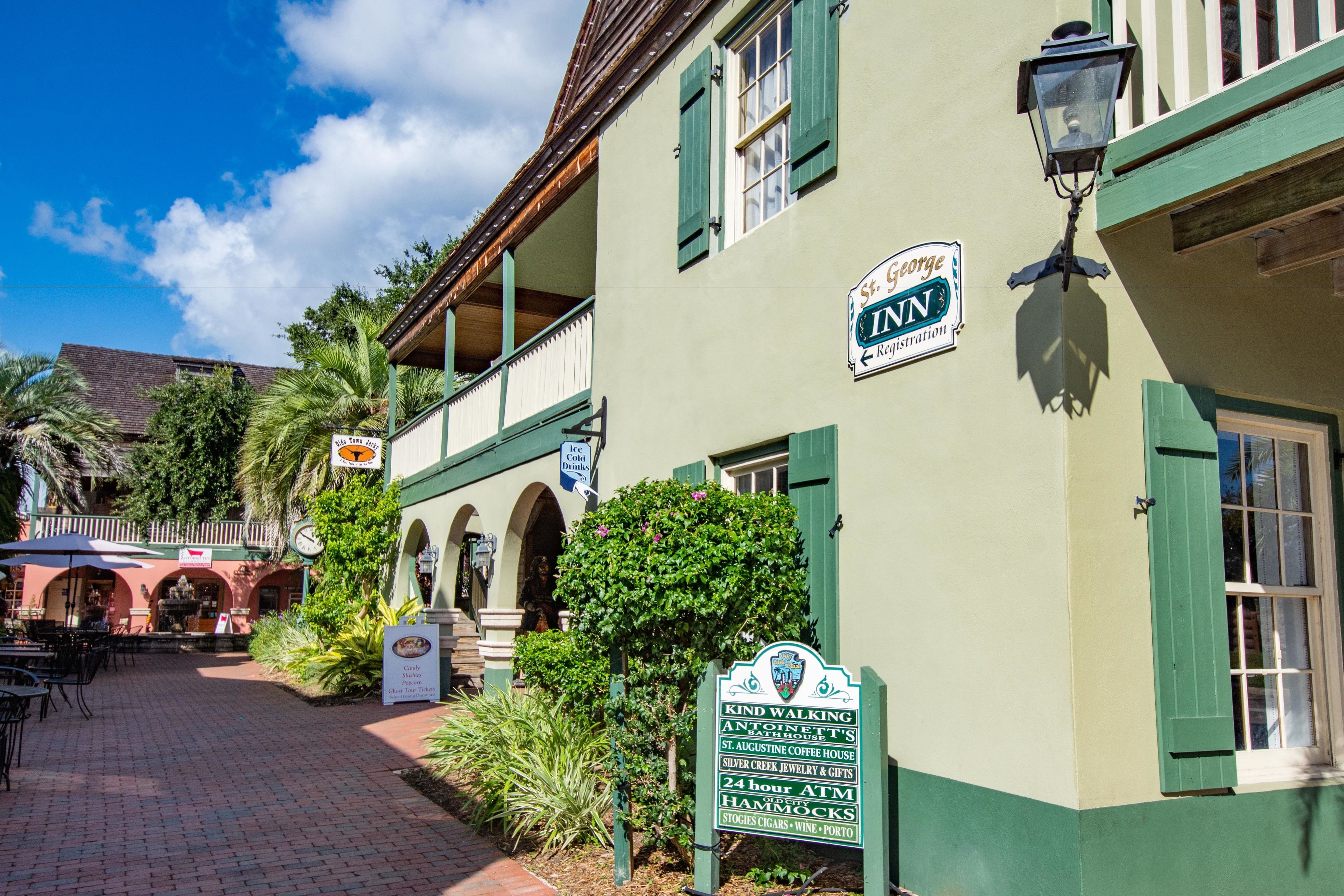 A building with a sign indicating it is the Inn, featuring a 24-hour ATM, hammocks, and a variety of amenities including a coffee house, jewelry store, and gift shop.