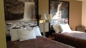 Habitación de hotel con dos camas, una mesita de noche, una lámpara y dos grandes pinturas de cascadas en la pared.