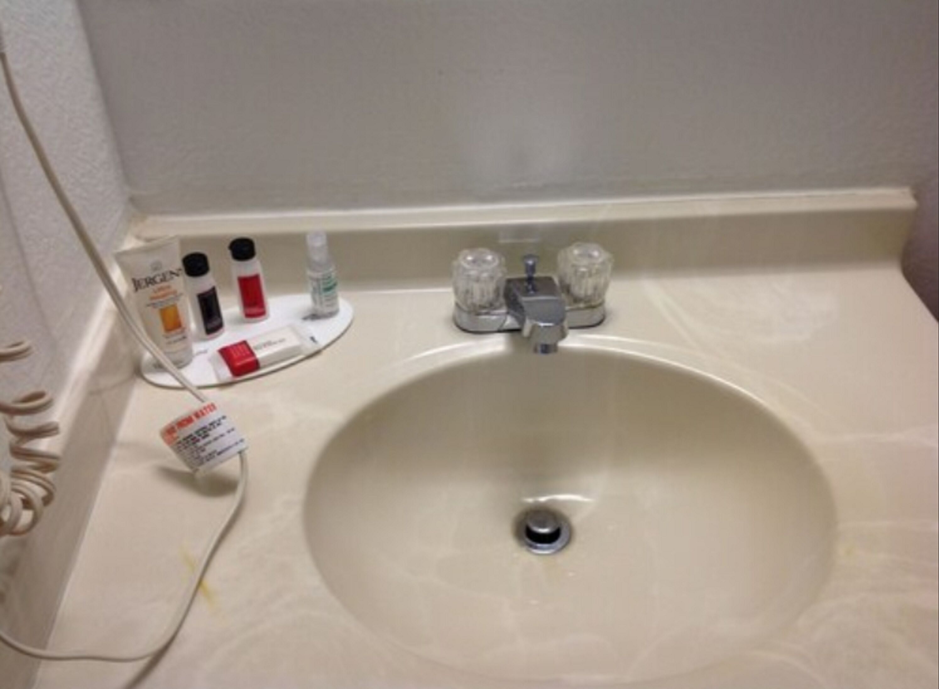 Un lavabo de salle de bain avec des articles de toilette et un sèche-mains.