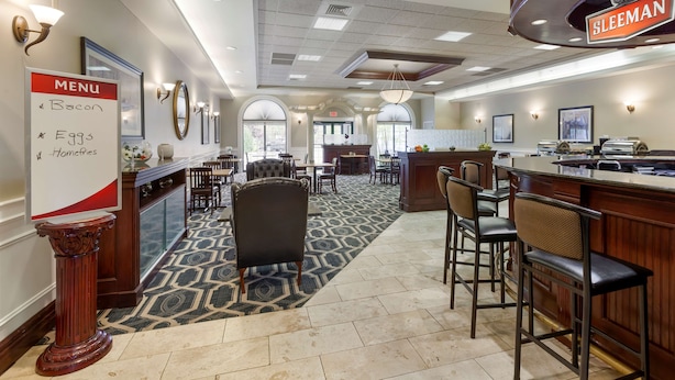 A hotel lobby with a bar area, a menu board, and a seating arrangement.