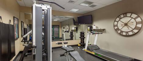 A gym with exercise equipment, a treadmill, and a large wall clock.