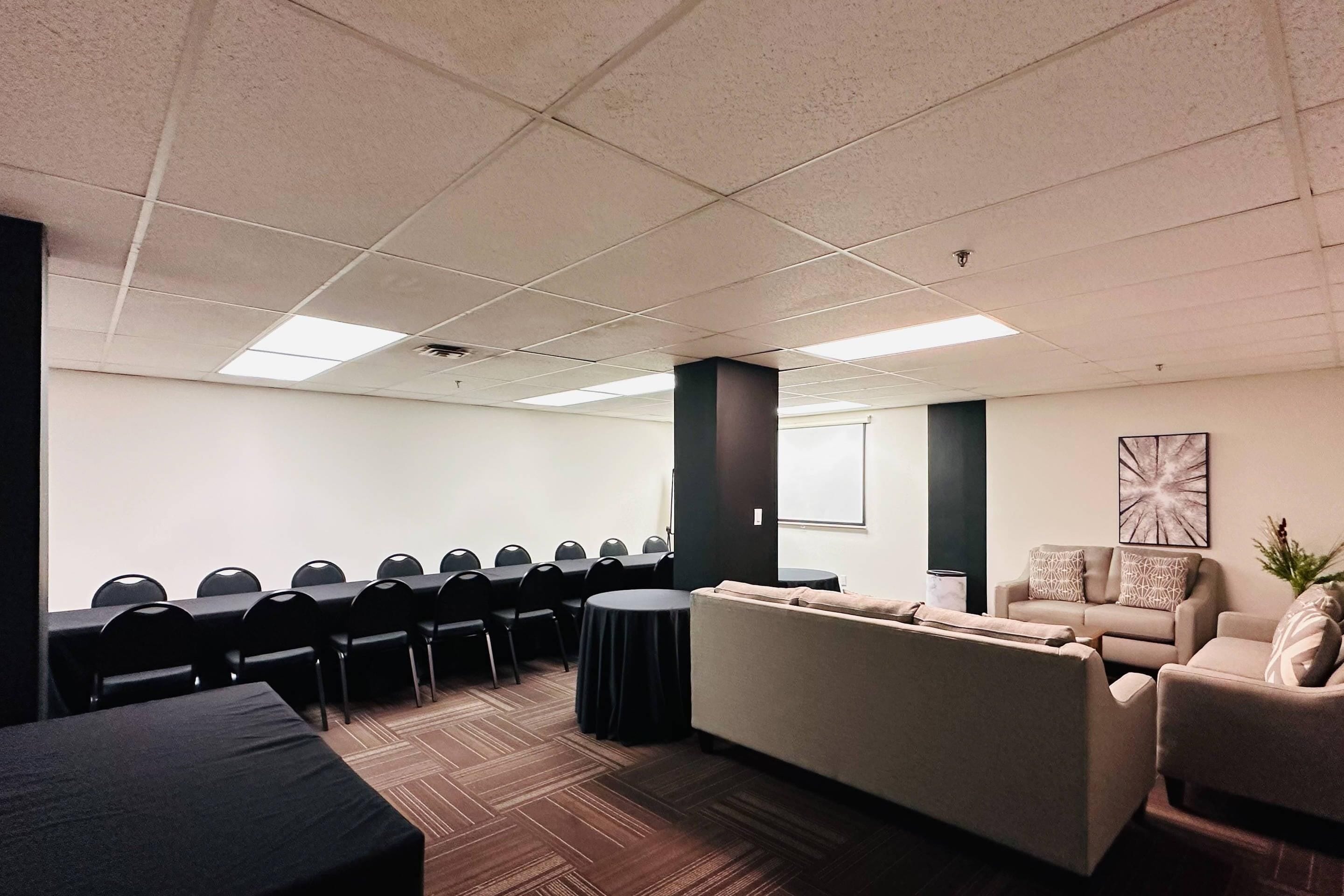 A conference room with a long table and chairs, a sofa, and a small round table.