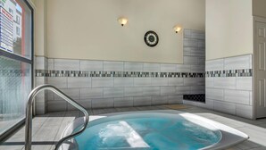Un espace détente avec un jacuzzi, des rampes en métal, des murs carrelés et une horloge au mur.