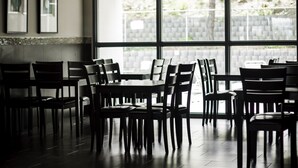 A dining area with tables and chairs, large windows with a view of greenery, and framed pictures on the wall. - Quality Inn (Kamloops)