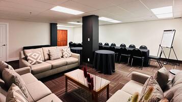 Sala de conferencias con sofá, mesa de centro y sillas dispuestas para reuniones.