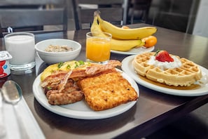 A breakfast plate with waffles, scrambled eggs, bacon, sausages, and toast. - Quality Inn (Kamloops)