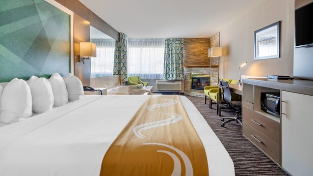 Une chambre d’hôtel avec un grand lit, un bureau avec une chaise, une télévision, une cheminée et une vue sur l’extérieur.