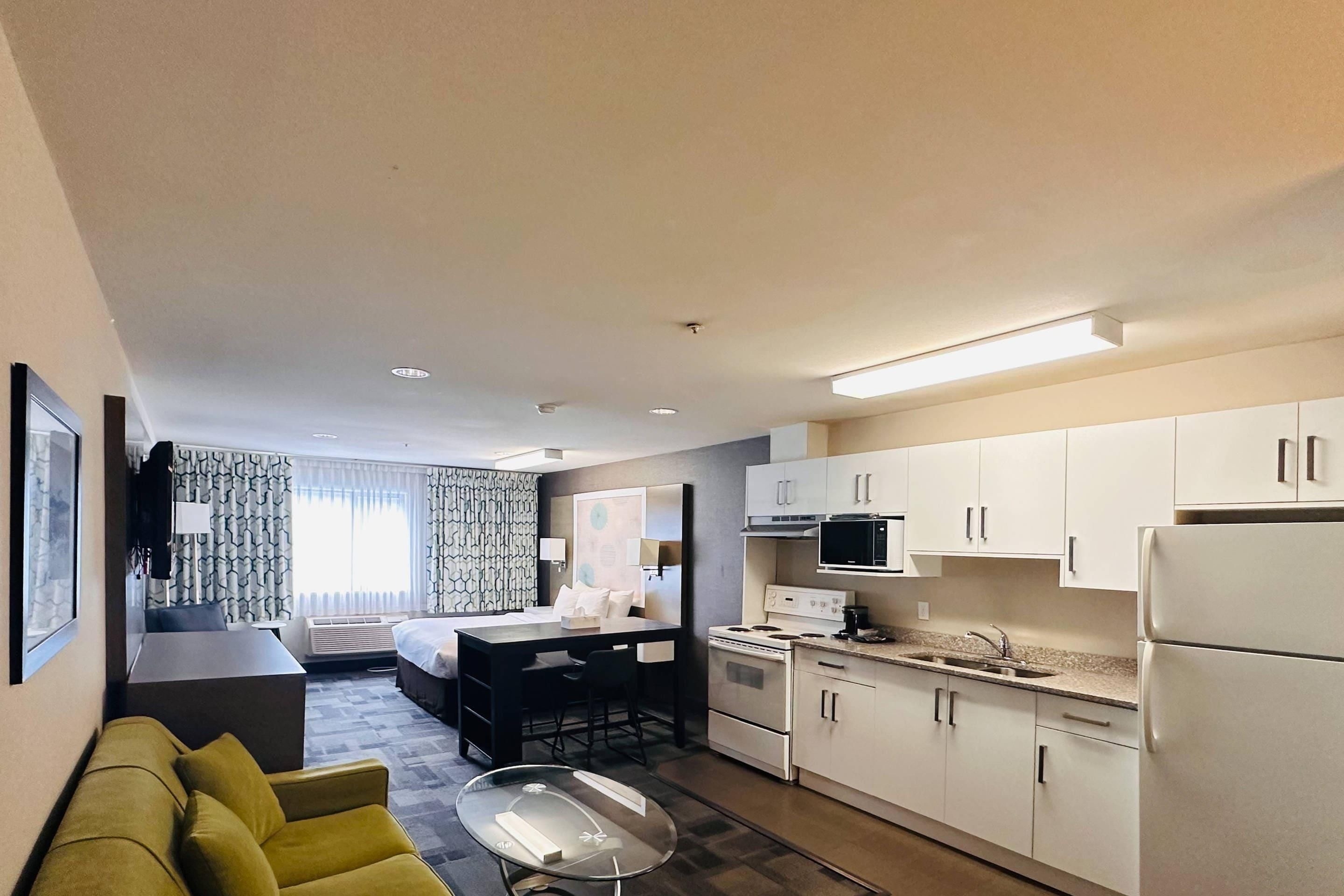 Une chambre d’hôtel compacte comprenant un coin cuisine, un espace repas et un canapé.