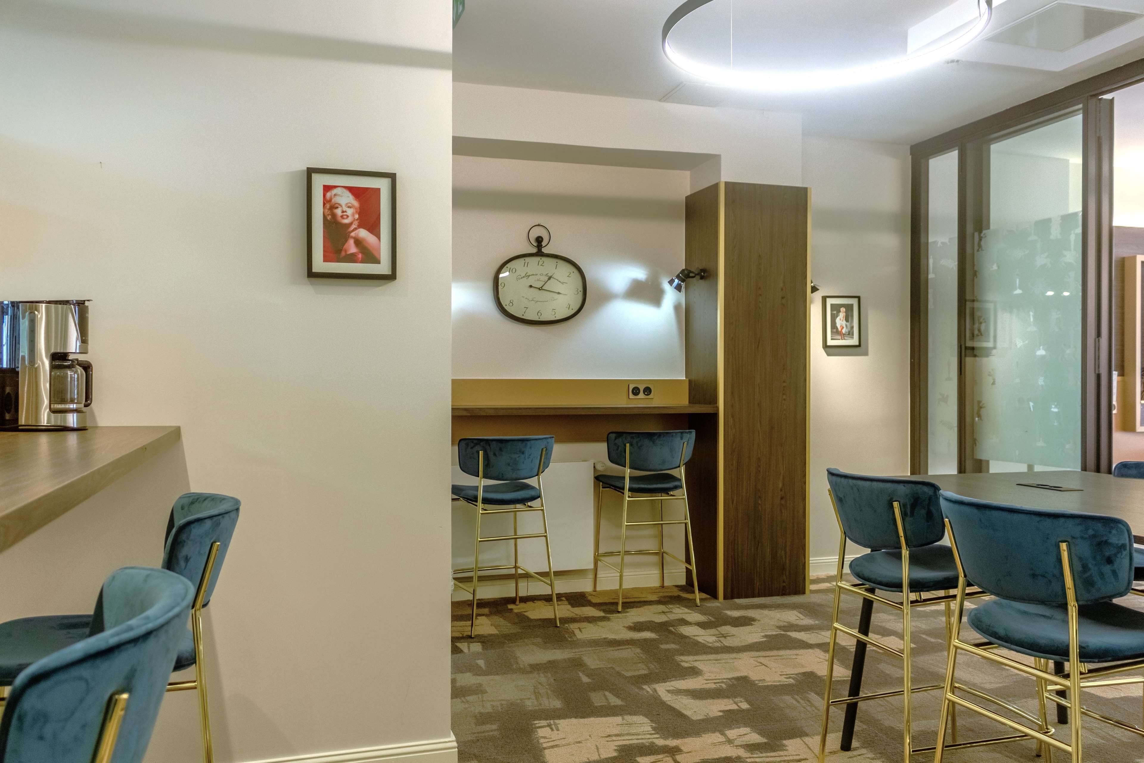 A modern dining area with blue chairs, a wooden table, and a clock on the wall.