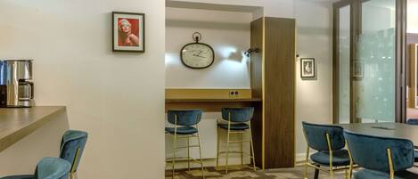 A modern dining area with blue chairs, a wooden table, and a clock on the wall.