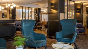 Eine moderne Lobby mit dunklem Mobiliar, einer Rezeption und einem großen Spiegel.