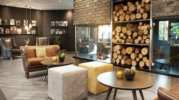 A modern lounge area with leather sofas, round tables, and a fireplace. - Radisson Blu Hotel Nydalen, Oslo (Oslo)