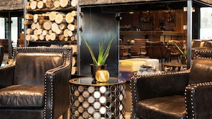 A cozy seating area with leather chairs, a round table with mirrors, and a potted plant. - Radisson Blu Hotel Nydalen, Oslo (Oslo)