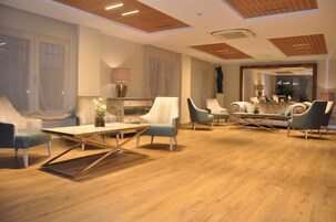 Un amplio salón con piso de madera, muebles modernos y un espejo grande que refleja la habitación.