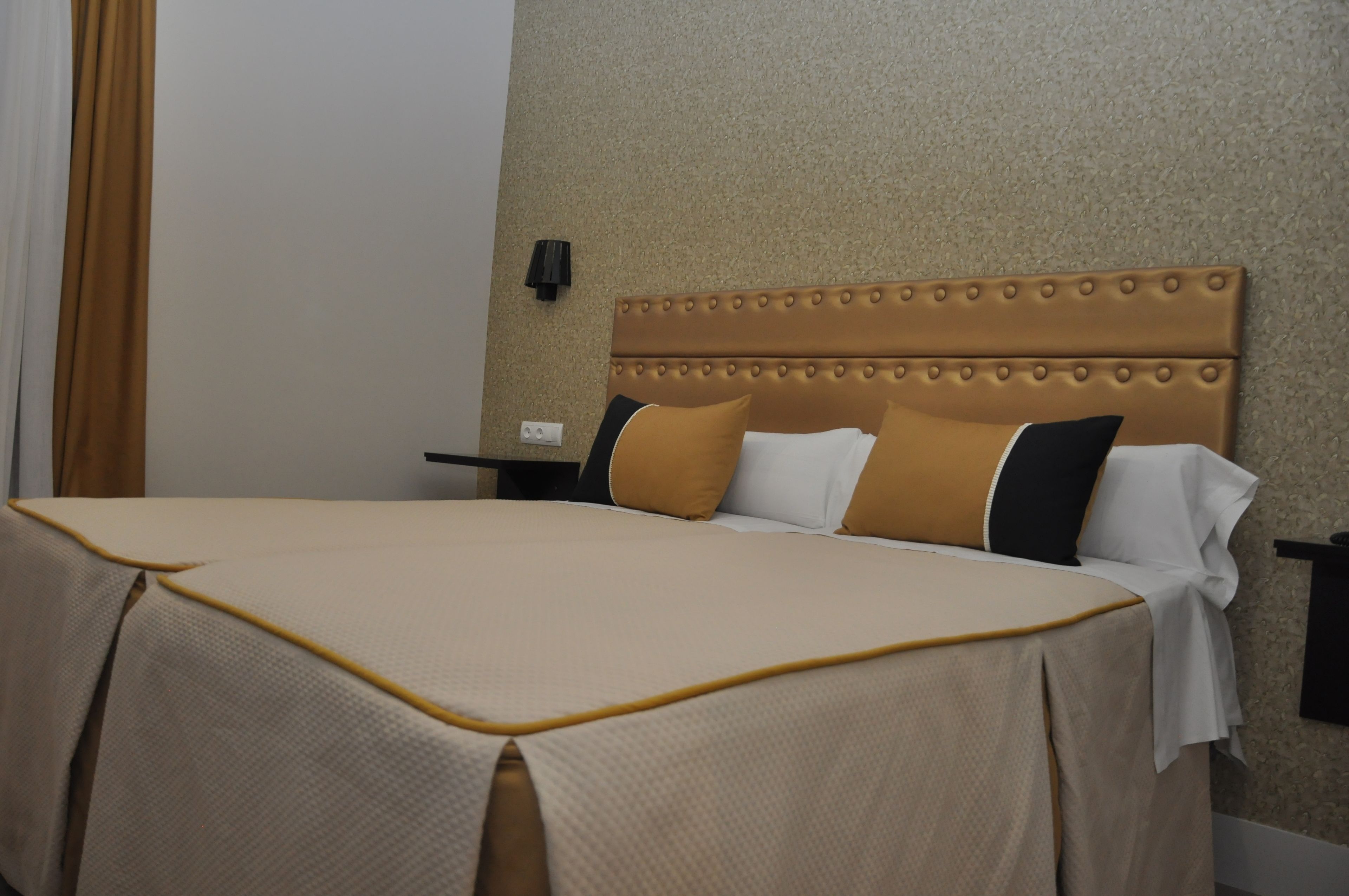 Una habitación de hotel con una cama grande, un cabecero y una mesita de noche.