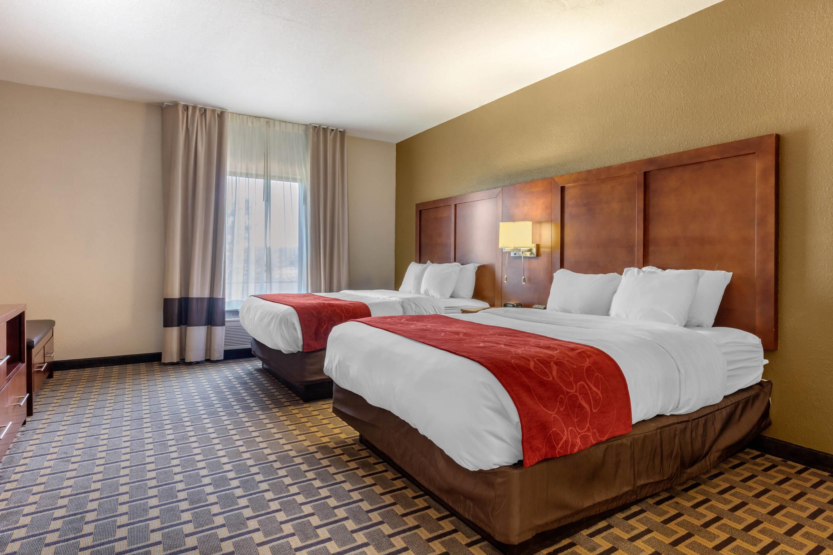 Habitación de hotel con dos camas, un escritorio y una ventana con cortinas.