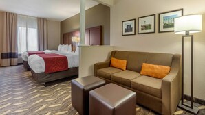 Una habitación de hotel con una cama, dos sofás, una mesita de centro y una lámpara.