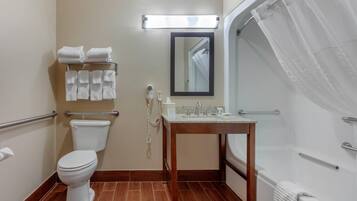A bathroom with a toilet, sink, and shower. There are towels on a rack and a mirror above the sink.