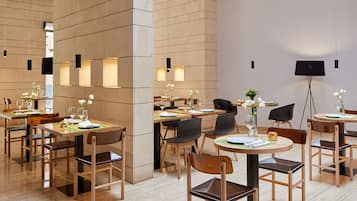 Un comedor moderno con mesas y sillas de madera, dispuesto en un espacio amplio.