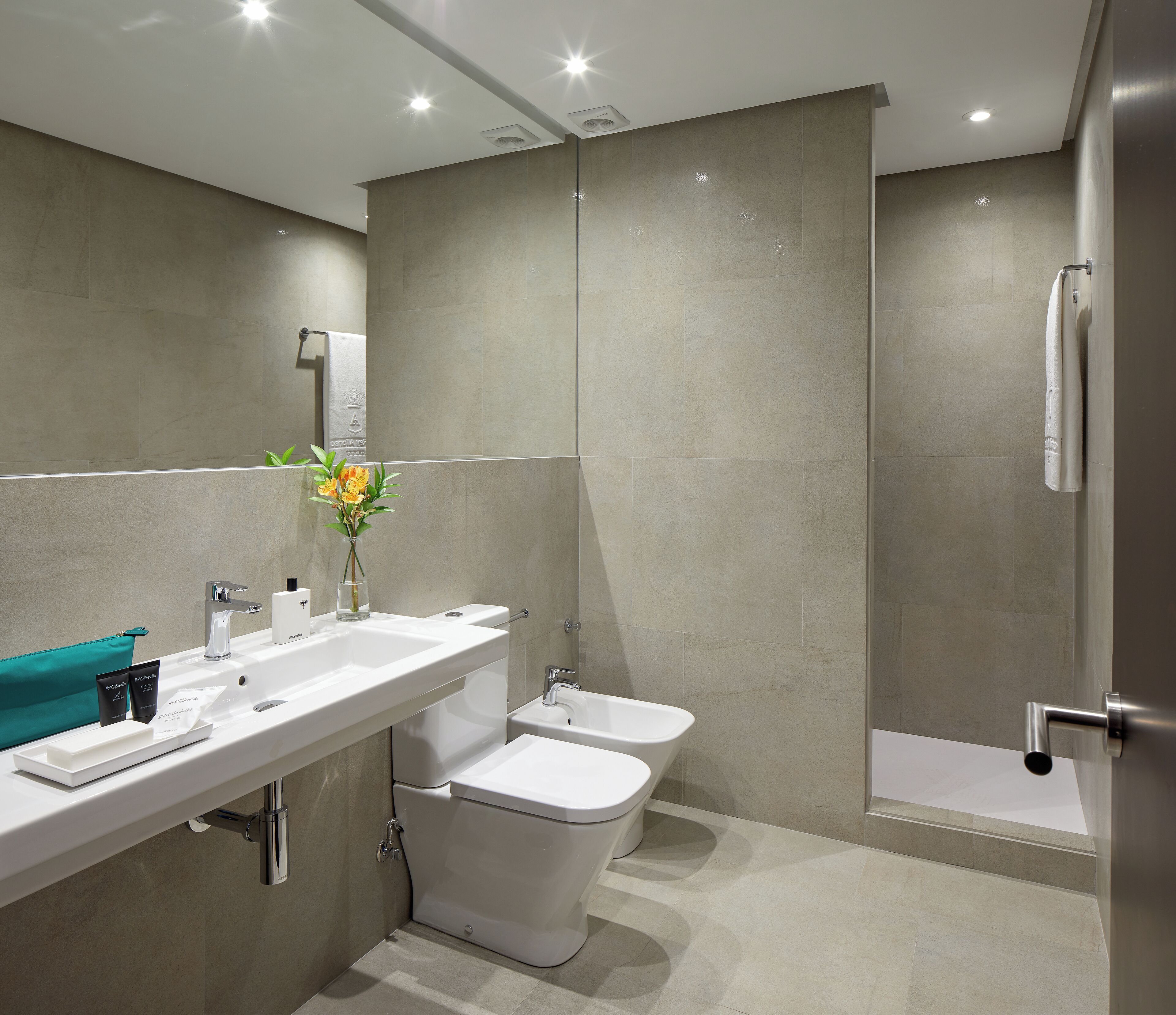 A modern bathroom with a sink, toilet, bidet, and shower.
