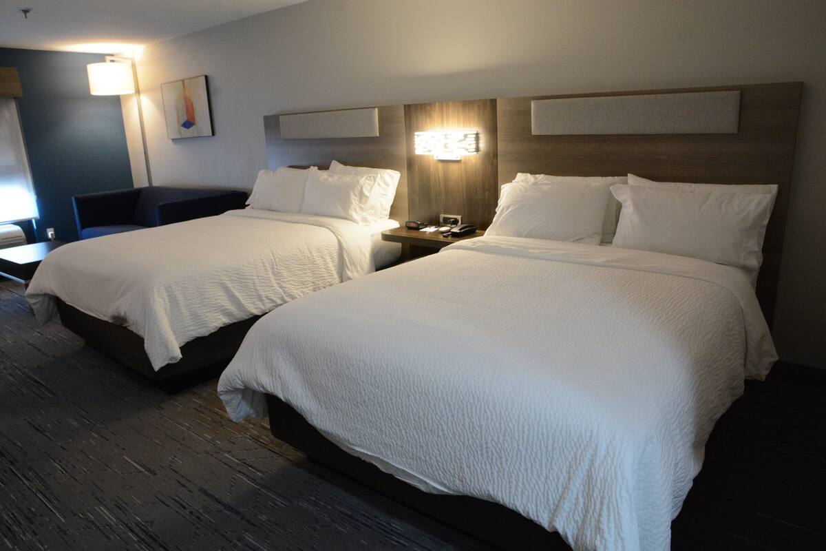 Une chambre d’hôtel avec deux lits, un bureau et une lampe.