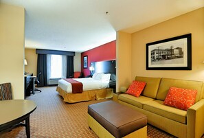 A hotel room with a bed, a sofa, a desk, and a chair.