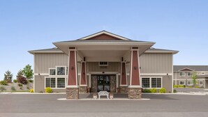 A two-story building with a covered entrance and a stone foundation. - Inn At Moses Lake with Extended Stay (Moses Lake)
