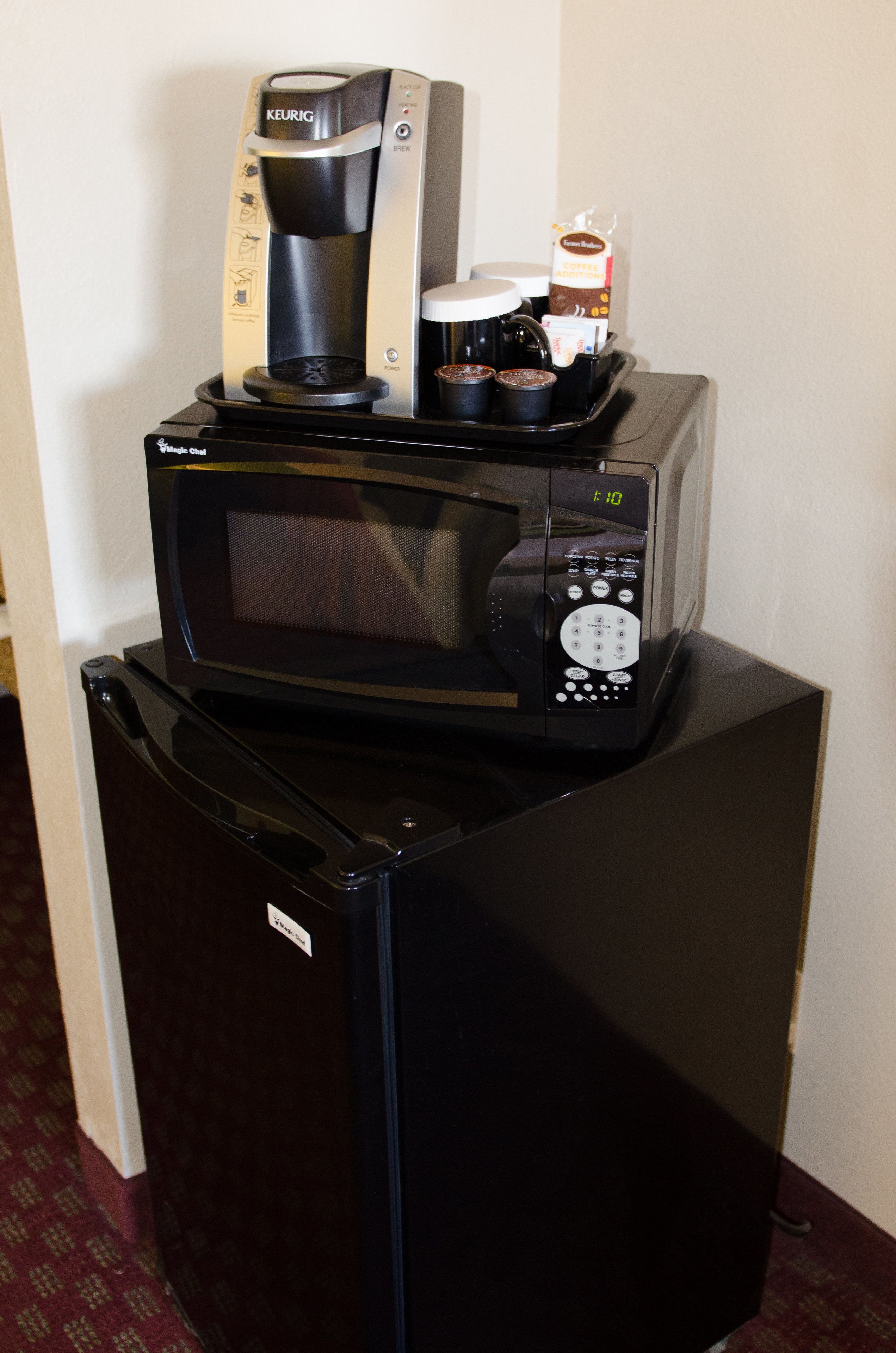Eine kleine Küchenzeile mit einer Mikrowelle und einer Kaffeemaschine auf einem Kühlschrank.