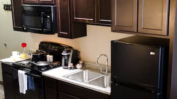 A kitchen with dark wooden cabinets, a black refrigerator, a microwave, and a stove.
