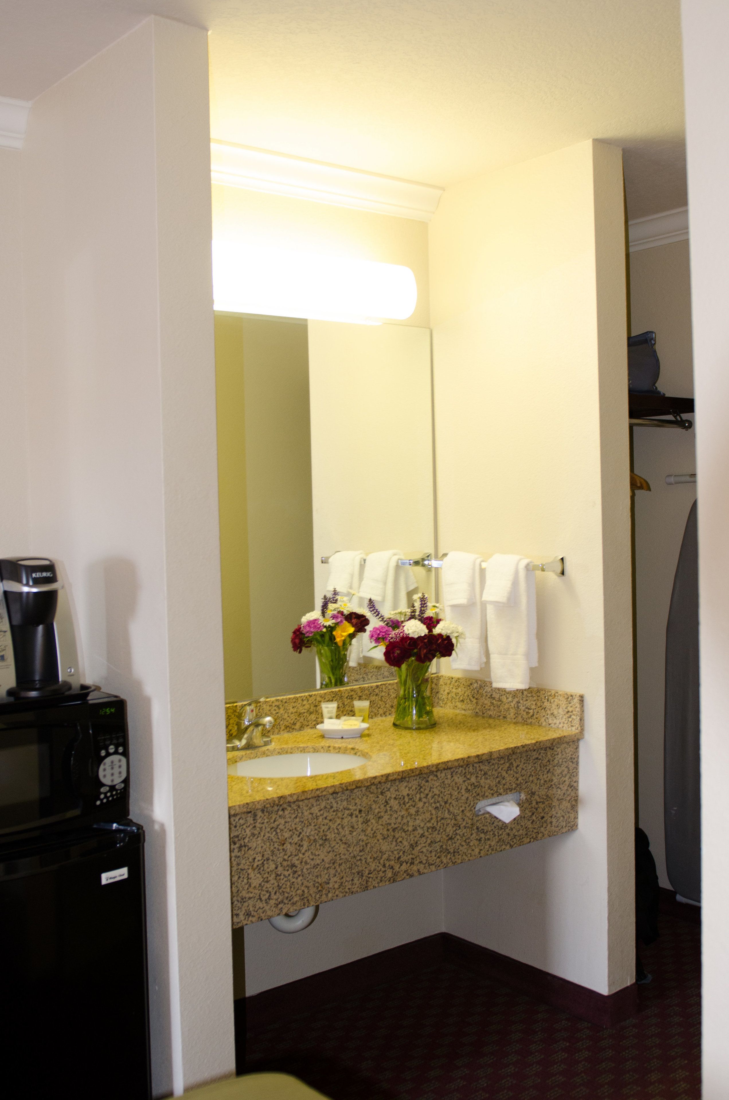 Un baño de hotel con lavamanos, espejo y cafetera.