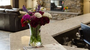 A reception area with a stone wall, a fireplace, and a vase of flowers on a counter. - Inn At Moses Lake with Extended Stay (Moses Lake)
