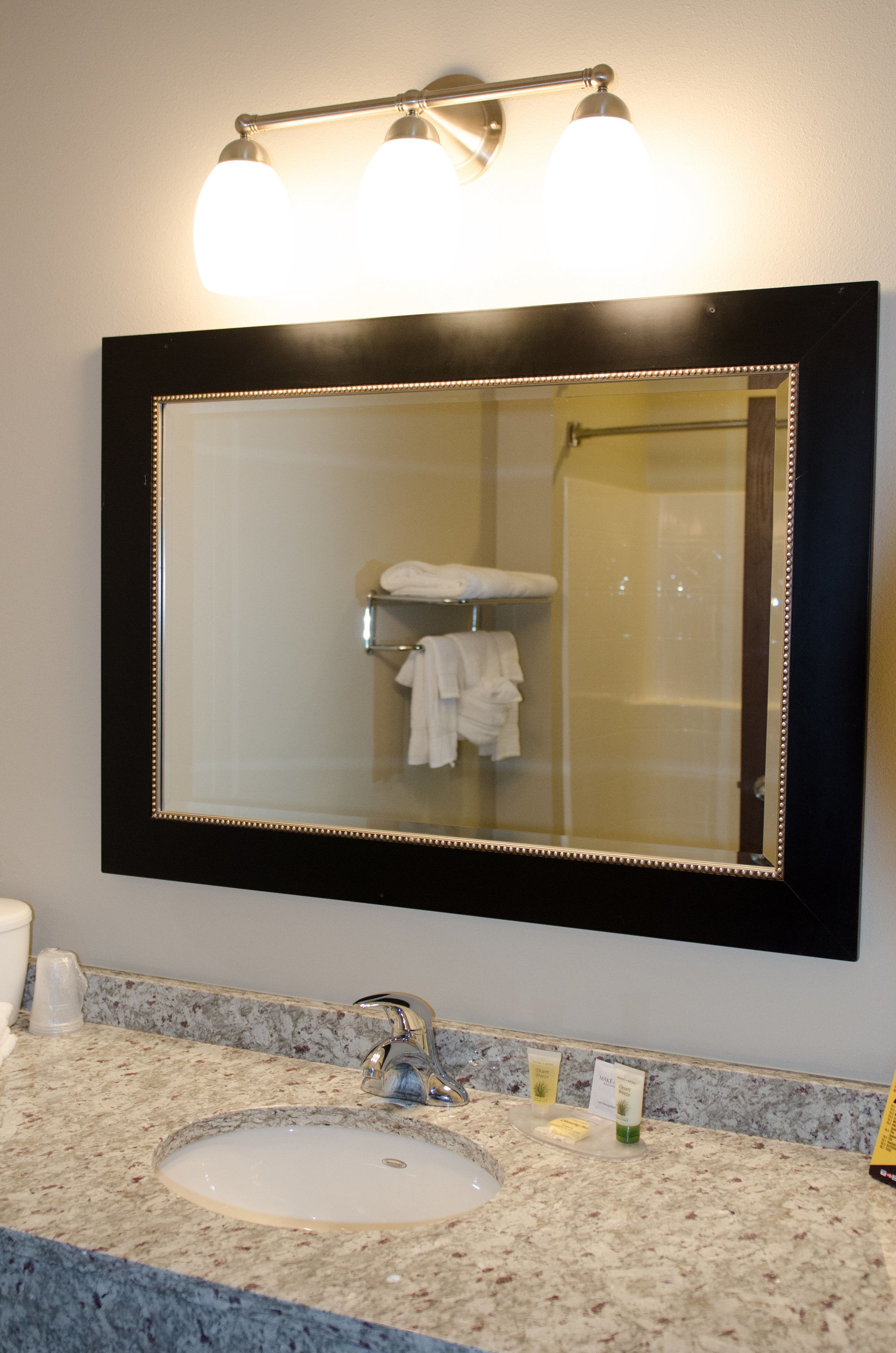 Une salle de bain avec un grand miroir, un lavabo et un porte-serviettes.