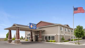 A hotel with a covered entrance, a flagpole with an American flag, and a sign for 'The Inn at Moses Lake'.