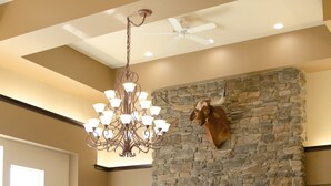 A spacious living room with a stone fireplace, a large chandelier, and a leather sofa. - Inn At Moses Lake with Extended Stay (Moses Lake)