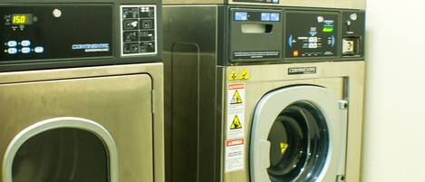 Two stainless steel front-loading washing machines in a commercial setting.