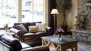 A spacious living room with a leather sofa, a coffee table, and a stone fireplace. - Inn At Moses Lake with Extended Stay (Moses Lake)