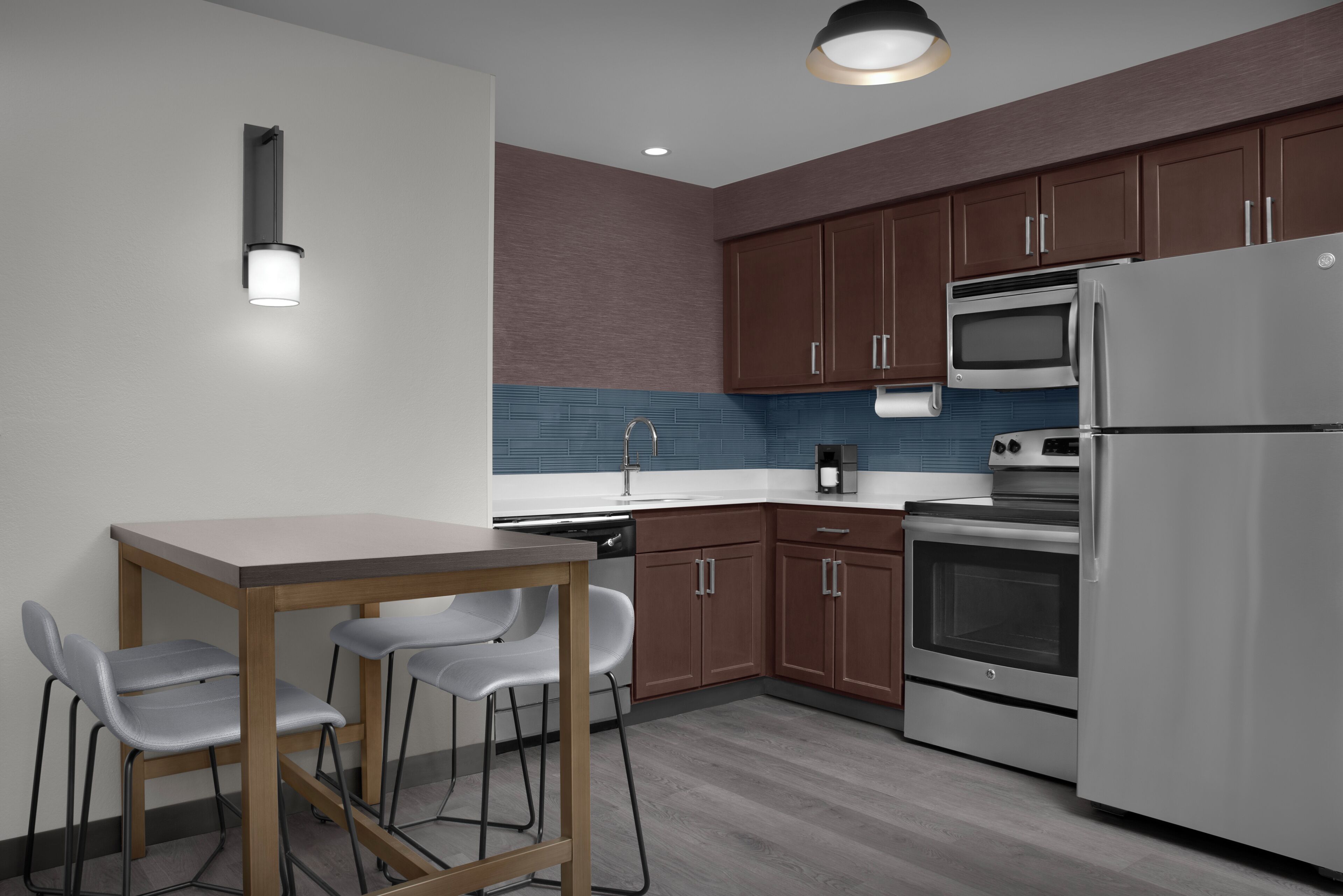 Una cocina moderna con una mesa de comedor y sillas, electrodomésticos de acero inoxidable y armarios de madera.