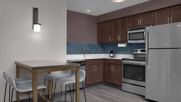 Una cocina moderna con una mesa de comedor y sillas, electrodomésticos de acero inoxidable y armarios de madera.