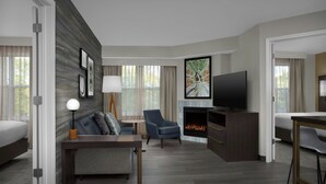 A hotel room with a bed, a desk, a chair, a TV, a fireplace, and artwork on the wall. - Residence Inn by Marriott Arundel Mills BWI Airport (Hanover)