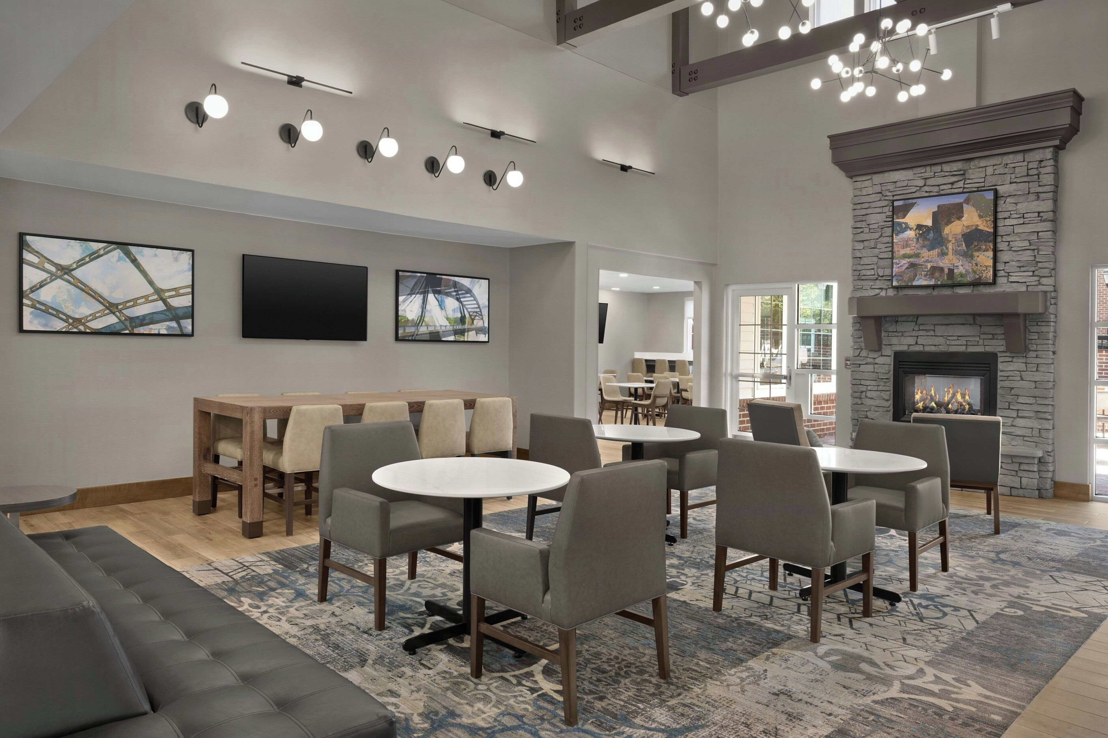 A modern hotel lobby with round tables, sofas, and artwork on the walls.
