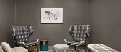 A room with two leather armchairs, a sofa, a small ottoman, and a bench with a plaid cushion.
