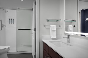 Un bagno moderno con cabina doccia in vetro, lavandino bianco con rubinetto cromato e uno specchio grande.