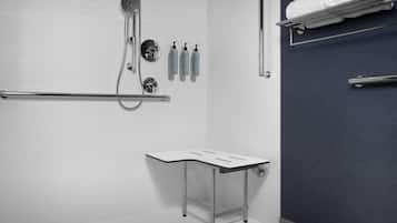Un baño con ducha, toallero y una mesita.