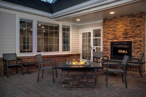 A patio with a stone fireplace, outdoor seating, and large windows. - Residence Inn by Marriott Arundel Mills BWI Airport (Hanover)