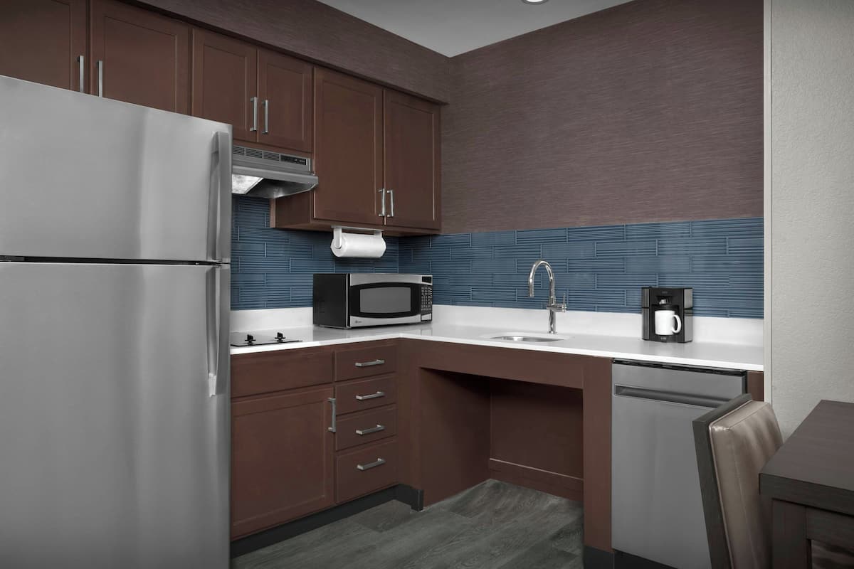 A compact kitchen with a refrigerator, microwave, coffee maker, and a sink.